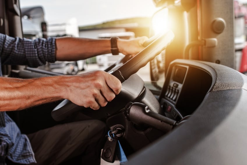 Persons hands on the wheel of a tilt tray truck driving 