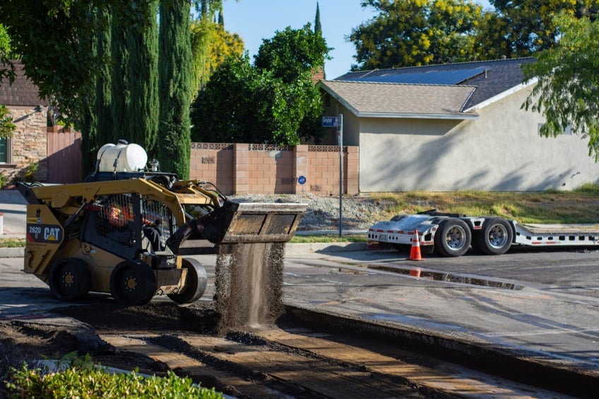 Skid steer pouring road base onto a roadworks site