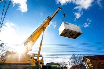 crane lifting generator on construction site