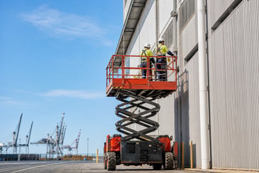 Diesel scissor lift elevating workers on an industrial shed in Townsville