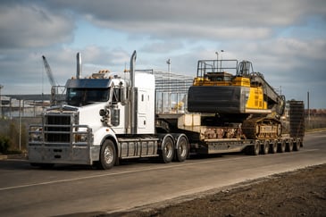 Prime mover truck hauling heavy equipment near an industrial project in Geelong
